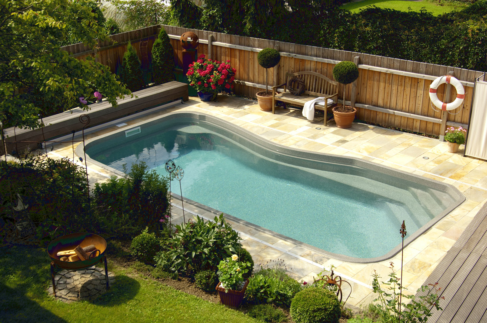 Pool im Garten mit Natursteinumrandung, Feuerschale und bepflanzter Terrasse