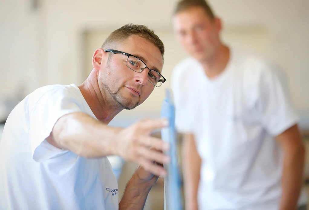 Poolbauer bei der Qualitätskontrolle eines Kunststoffprofils in der Werkstatt